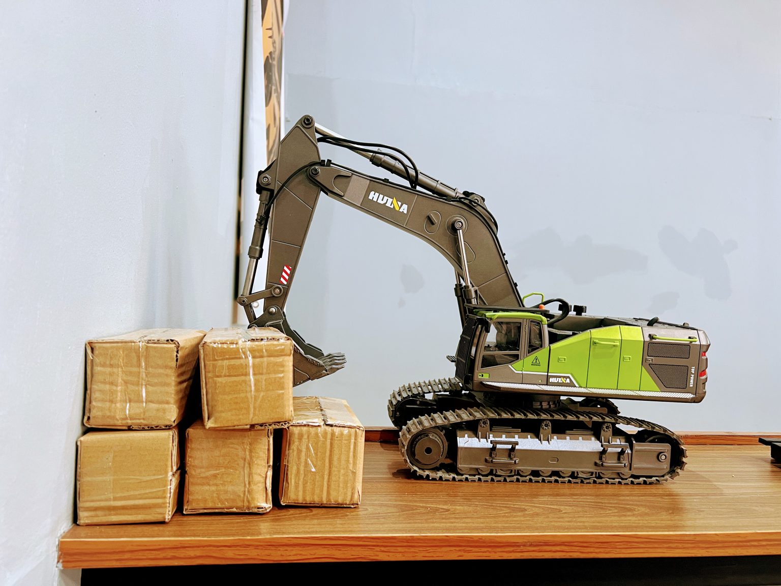 木质桌面上的玩具挖掘机模型与小纸板箱