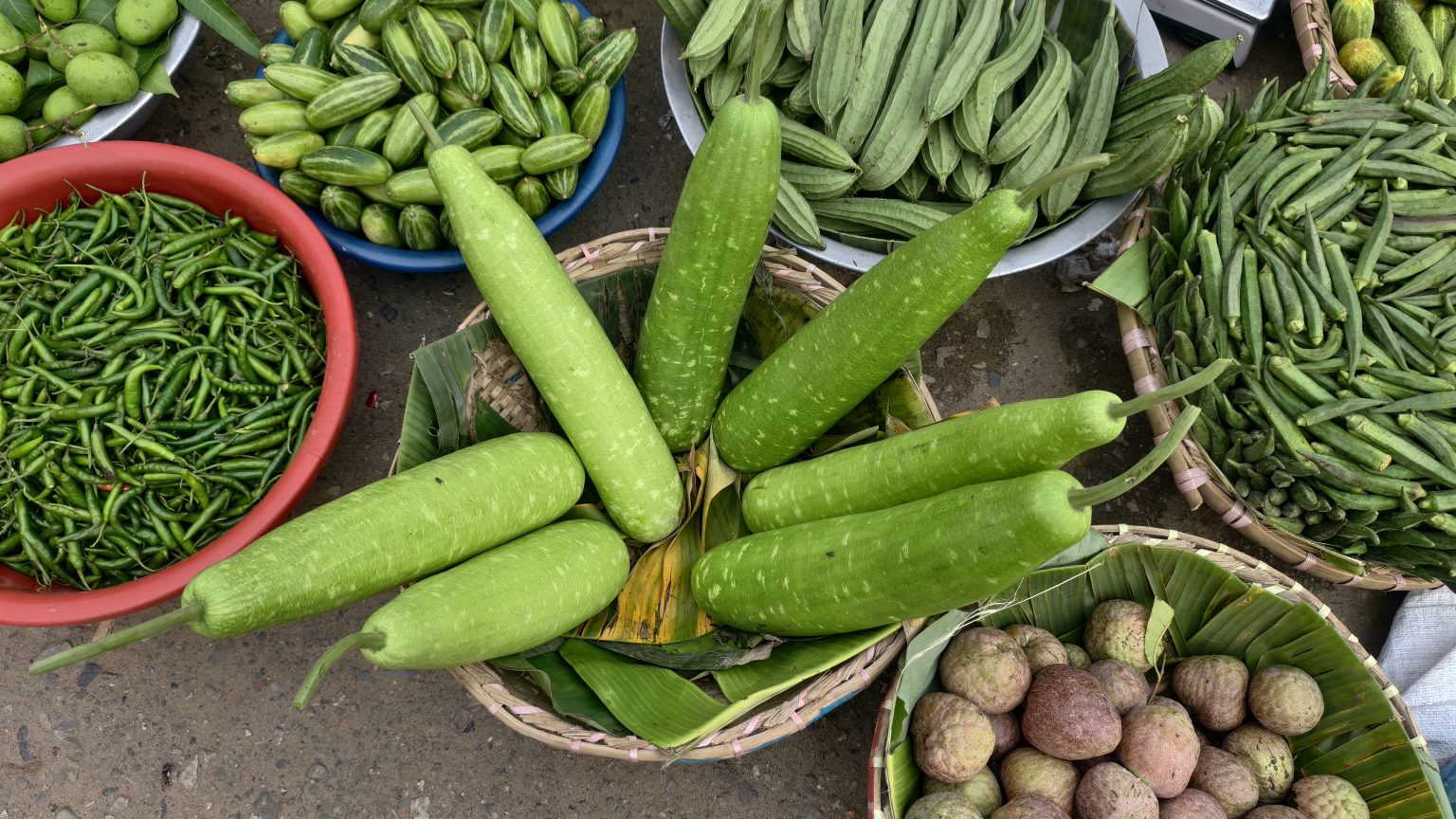 市场葫芦、秋葵、丝瓜及青辣椒等蔬菜陈列，拍摄地未明确的食品采购背景资料照片
