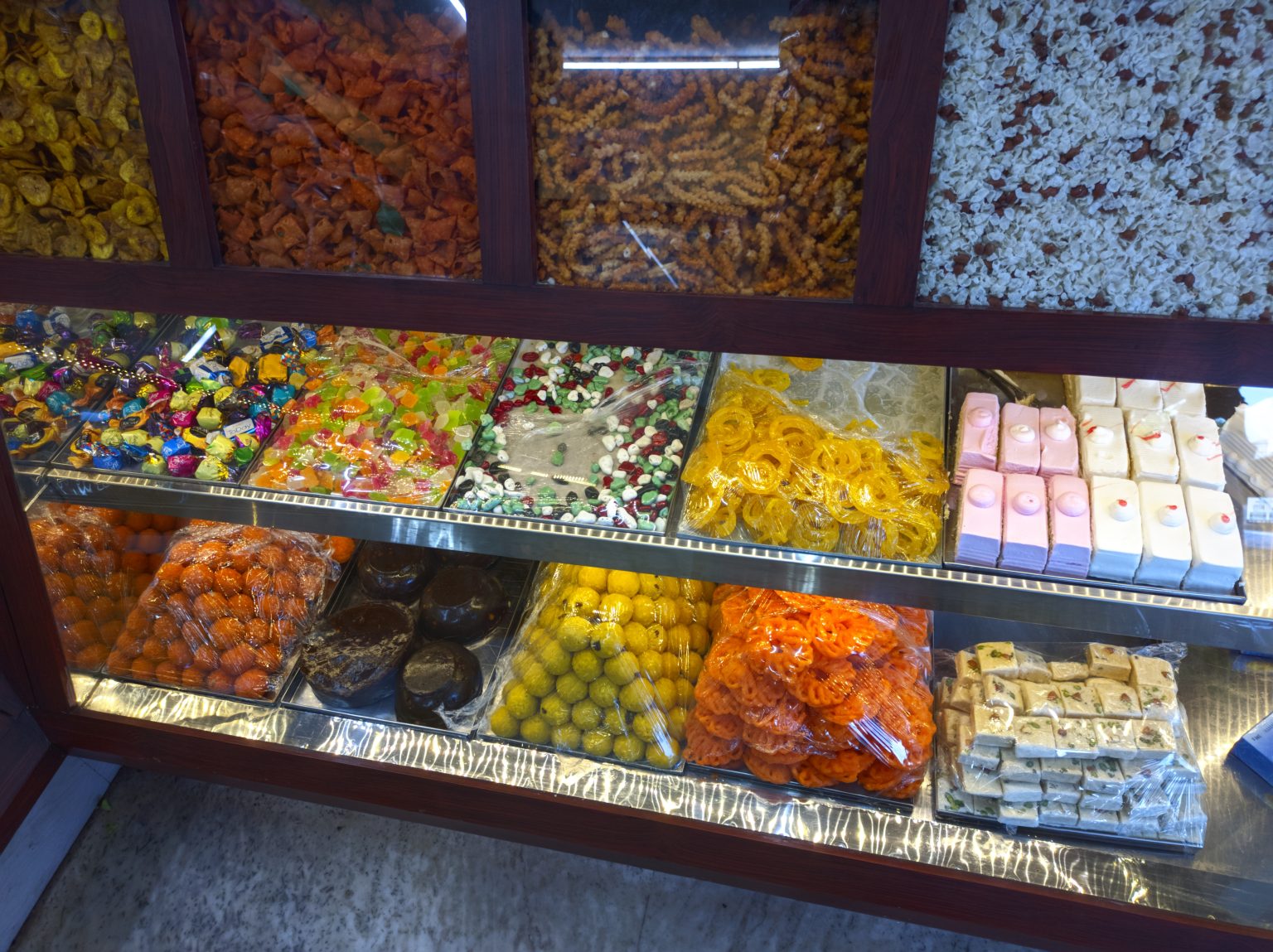 食品门店柜内陈列的糖果与糕点，食品零售场所背景资料照片，具体门店地点未明确