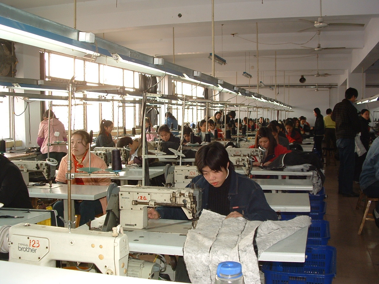 服装工厂内操作缝纫机的工人资料照片