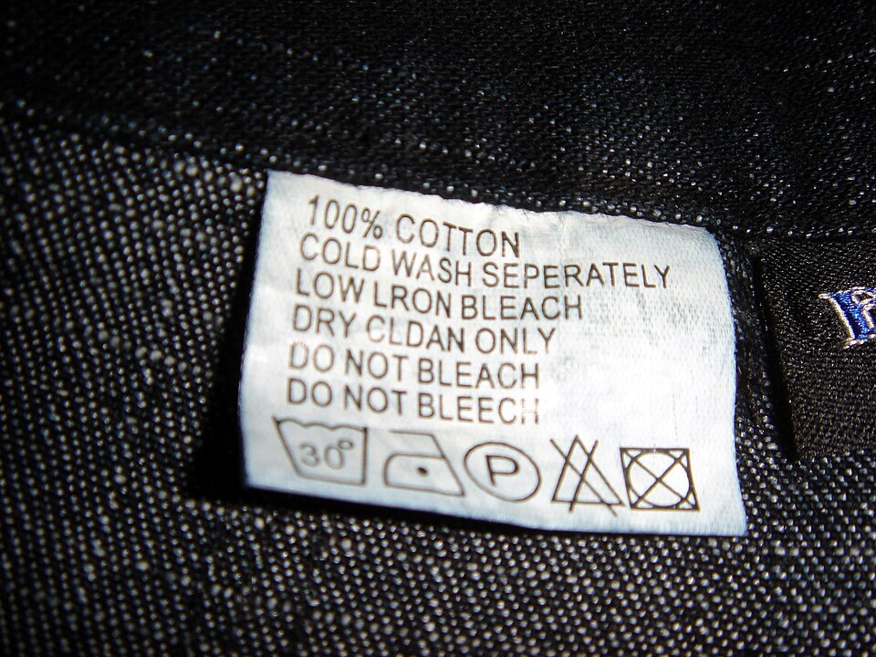 标有100% cotton并出现相互矛盾洗护说明的服装标签资料照片，保留原标签问题，不作为正确标签示范